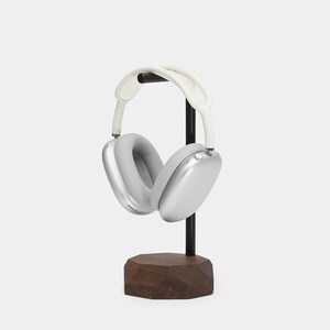 May include: Silver headphones with white earcups and a black stand with a wooden base.