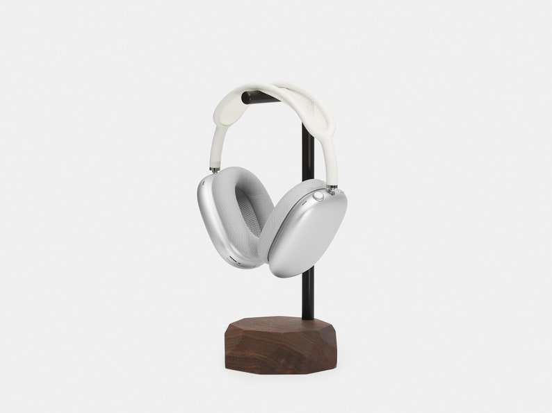 May include: Silver headphones with white earcups and a black stand with a wooden base.
