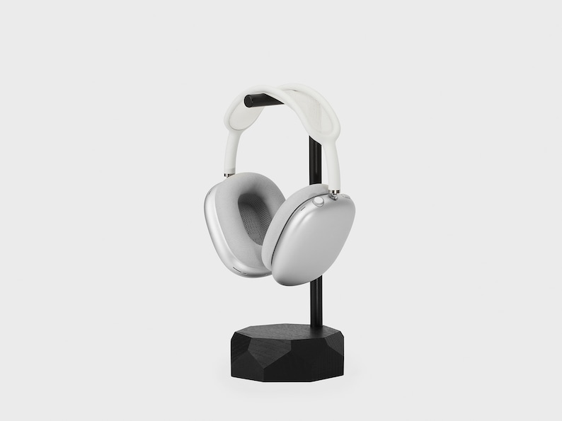 May include: Silver headphones with a white headband, resting on a black stand with a geometric base.