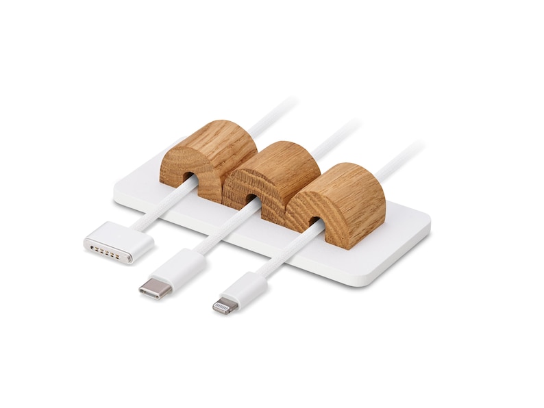 May include: A white cable tidy featuring three wooden cable holders. The cylindrical wooden holders are set on a white rectangular base. Three white cables with different connectors are inserted through the wooden holders.