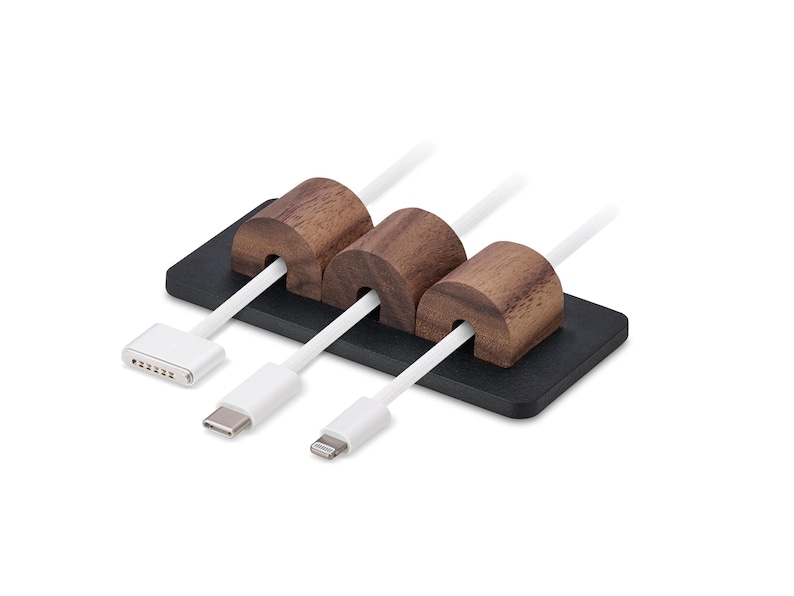 May include: A cable tidy with three slots, each holding a white cable. The tidy has a black base and three brown wooden cable holders. The cables have different connector types.