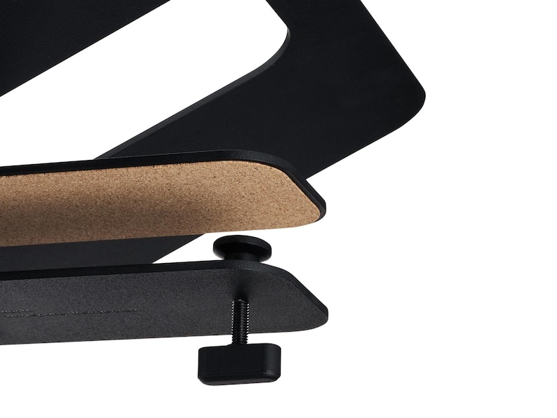 May include: A black metal desk clamp with a cork pad and adjustable screw. The clamp is designed to hold a laptop or other device. The design is modern and minimalist.