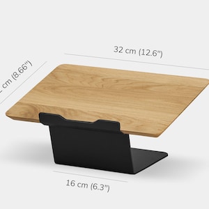 May include: A wooden laptop stand with a light brown wood grain surface and a black metal base. The stand measures 32 cm (12.6 inches) in width, 22 cm (8.66 inches) in depth, 15 cm (5.9 inches) in height, and has a 16 cm (6.3 inches) base width.