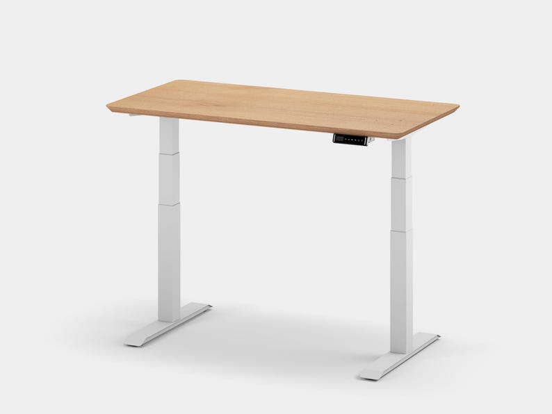 May include: A white electric standing desk with a light wood top. The desk has a control panel on the side of the top.