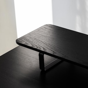 May include: Black wooden desk organizer with a metal frame. The organizer is sitting on a black desk.