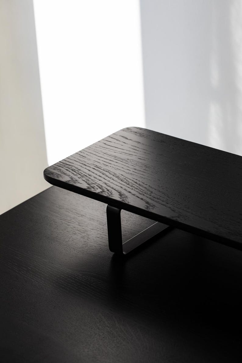 May include: Black wooden desk organizer with a metal frame. The organizer is sitting on a black desk.