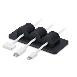 May include: A black cable tidy with three slots, holding white charging cables with different connector types. The tidy is rectangular with rounded edges, and the cable holders are cylindrical.