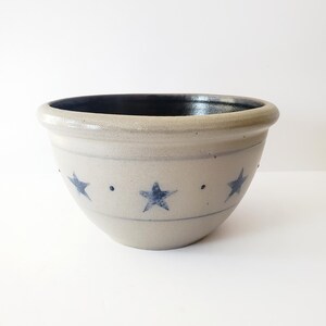May include: A large, off-white ceramic mixing bowl with a dark blue glaze inside. The bowl has a blue and white star pattern around the outside.