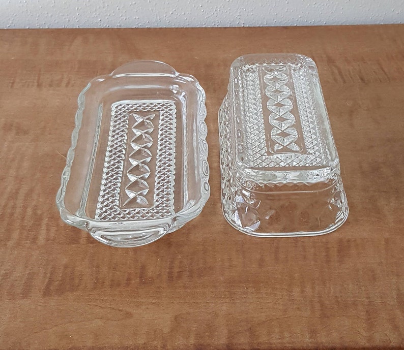 May include: Two clear glass butter dishes with a diamond pattern. The dishes are rectangular and have a raised edge.