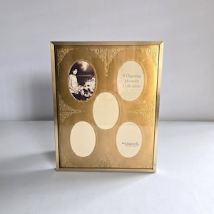 May include: A rectangular gold-toned picture frame featuring five oval openings for photographs. The frame has an ornate, embossed gold border pattern and includes the text 5 Opening Memory Collection by Intercraft The Frame People.