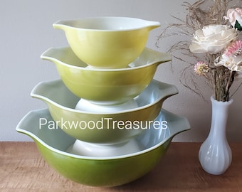 May include: A set of three green and white mixing bowls, stacked on top of each other. The bowls are made of glass and have a vintage look.