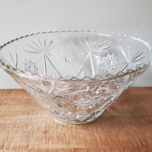 May include: A clear glass punch bowl with a starburst pattern. The bowl has a scalloped edge and is ideal for serving punch or other beverages.
