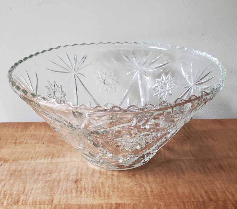 May include: A clear glass punch bowl with a starburst pattern. The bowl has a scalloped edge and is ideal for serving punch or other beverages.