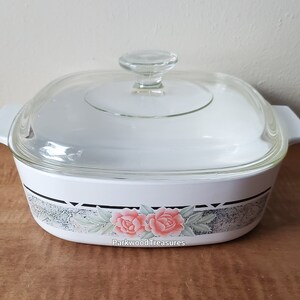 May include: White square baking dish with a glass lid. The dish has a floral design with pink roses and green leaves on a gray background. The text "Parkwood Treasures" is printed on the bottom of the dish.