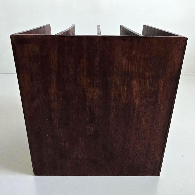 May include: A dark brown wooden organizer with a square base and angled sides. The top has several vertical dividers, creating multiple compartments. The wood grain is visible, giving it a natural look. The organizer is likely for desk or office use.