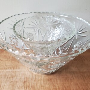 May include: A set of two clear glass bowls with a starburst pattern. The bowls are nested together.