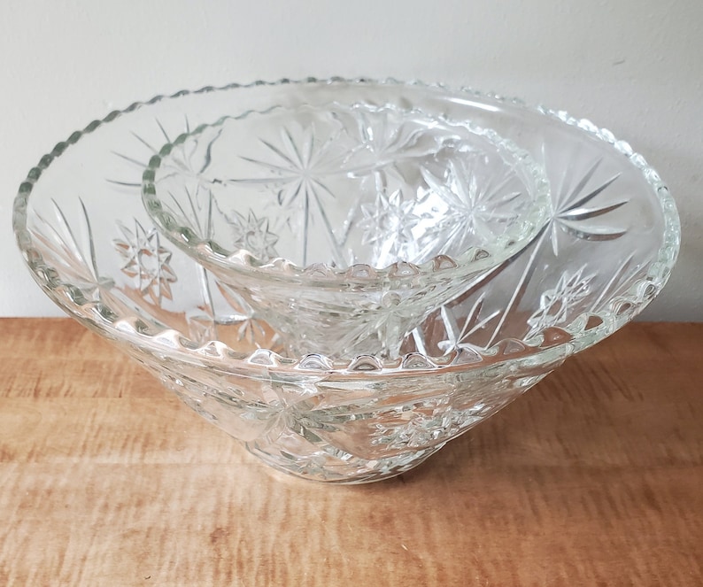 May include: A set of two clear glass bowls with a starburst pattern. The bowls are nested together.