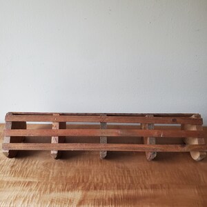 May include: A rustic wooden shelf with five hooks, perfect for hanging keys, towels, or other small items. The shelf is made of natural wood and has a distressed finish.