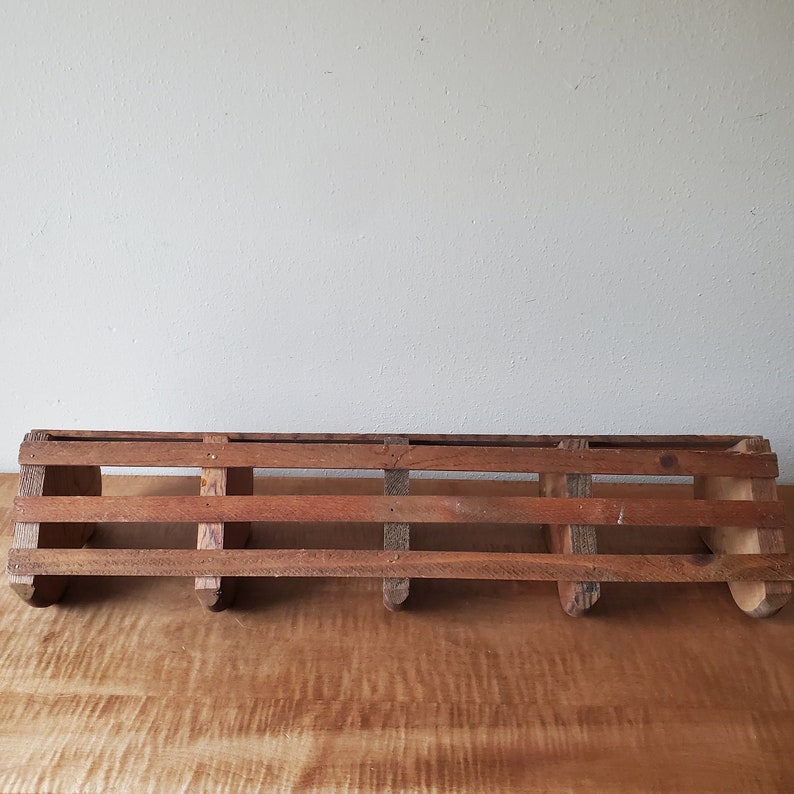 May include: A rustic wooden shelf with five hooks, perfect for hanging keys, towels, or other small items. The shelf is made of natural wood and has a distressed finish.