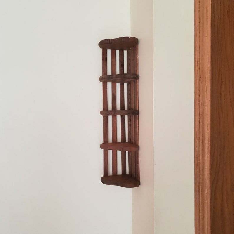 May include: A dark brown wooden corner shelf with four shelves. The shelf is mounted on a white wall.