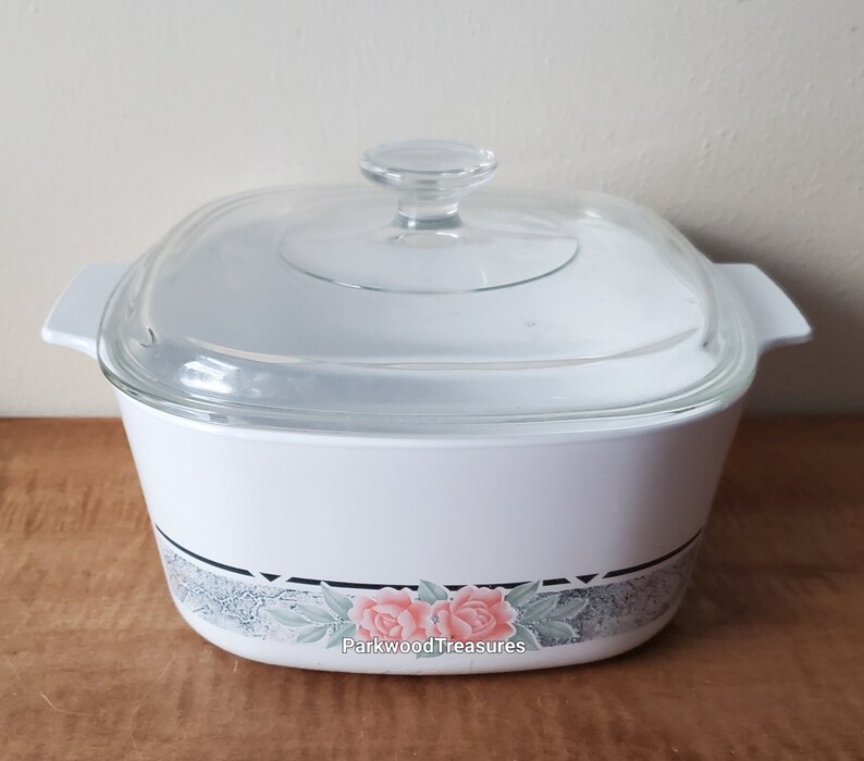 May include: White square baking dish with a glass lid. The dish has a floral design with pink roses and green leaves on a gray background. The text "Parkwood Treasures" is printed on the bottom of the dish.