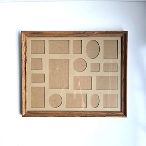 May include: A rectangular collage picture frame with a medium-toned wood grain finish. The frame contains a beige mat board featuring fifteen varied cutouts, including rectangular, square, circular, and oval shapes for displaying multiple photos.