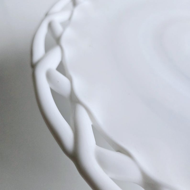 May include: White ceramic plate with a decorative woven edge.