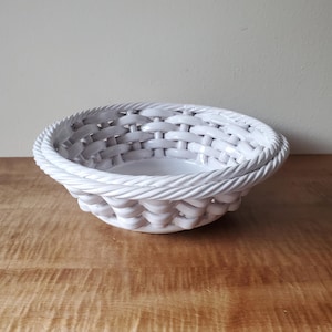 May include: White ceramic bowl with a woven design. The bowl is round and has a wide rim.
