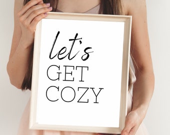 May include: White framed print with black text that reads "Let's Get Cozy".