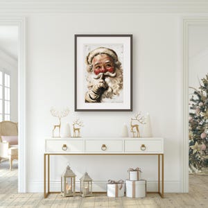 Może przedstawiać: Ramka z nadrukiem vintage ilustracją Świętego Mikołaja z białą brodą i czerwonymi policzkami. Trzyma palec przy ustach, jakby chciał powiedzieć "cisza".