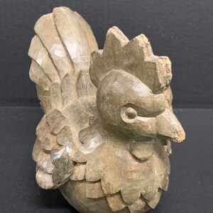 Puede incluir: Una figurita de gallo de madera tallada a mano con un dise&ntilde;o detallado. El gallo es marr&oacute;n y tiene una cresta y un pico prominentes.