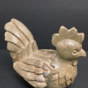 Puede incluir: Una figurita de pollo de madera tallada a mano con un dise&ntilde;o detallado. El pollo es marr&oacute;n y tiene una cresta y una papada prominentes.