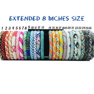May include: A display of 26 colorful beaded bracelets, each with a unique pattern, arranged in a row on a black stand. The bracelets are labeled with numbers 1 through 26. The text "EXTENDED 8 INCHES SIZE" is displayed above the bracelets.