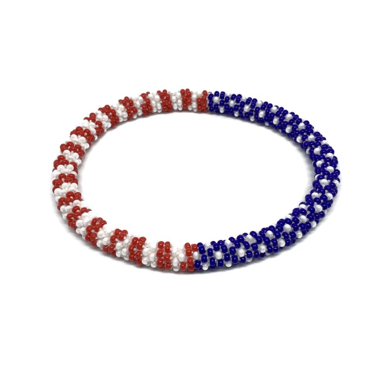 May include: A red, white, and blue beaded bracelet. The beads are arranged in a striped pattern.