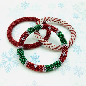 May include: Three beaded bracelets in red, white, and green colors. The bracelets are made of small beads and are stacked on top of each other.
