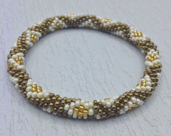 Bracelet de perles népalais fait main par Ramila. Bracelets hippie marron, dorés et blancs.