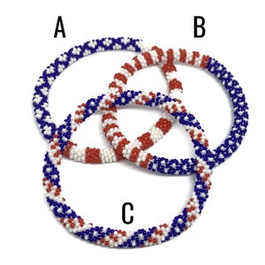 May include: Three beaded bracelets in red, white, and blue colors. The bracelets are woven in a pattern that resembles the American flag.