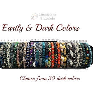 Puede incluir: Una colección de 30 pulseras de cuentas en varios colores oscuros, exhibidas sobre un fondo blanco. Las pulseras están numeradas y dispuestas horizontalmente. El texto dice "Earthly & Dark Colors" y "Elige entre 30 colores oscuros."