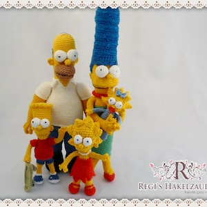 Puede incluir: Una familia de muñecos de ganchillo, que se asemejan a personajes de una popular serie animada. Los muñecos incluyen un padre, una madre y tres hijos de piel amarilla, cada uno con rasgos y ropa distintos. El padre lleva una camisa blanca y pantalones azules.