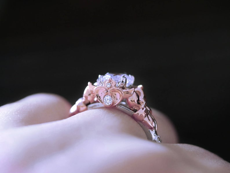 Puede incluir: Un anillo de compromiso de oro rosa con una piedra central grande y transparente y piedras de acento m&aacute;s peque&ntilde;as. El anillo est&aacute; engastado en un dise&ntilde;o delicado e intrincado.