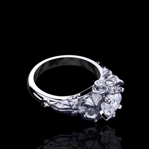 Puede incluir: Un anillo de plata con un gran diamante central claro y diamantes m&aacute;s peque&ntilde;os engastados en la banda. La banda est&aacute; dise&ntilde;ada de forma intrincada con motivos florales.