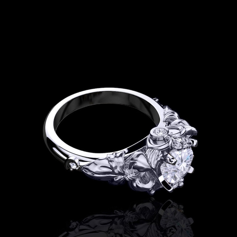 Puede incluir: Un anillo de plata con un gran diamante central claro y diamantes m&aacute;s peque&ntilde;os engastados en la banda. La banda est&aacute; dise&ntilde;ada de forma intrincada con motivos florales.