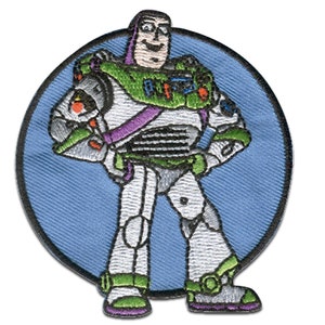 Könnte beinhalten: Ein blauer und weißer gestickter Aufnäher von Buzz Lightyear aus der Toy Story-Filmreihe. Buzz steht mit verschränkten Armen da und trägt seine charakteristische Space-Ranger-Uniform.
