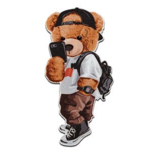 Può includere: Toppa a forma di orsetto marrone con berretto nero, maglietta bianca, pantaloni marroni e scarpe da ginnastica bianche e nere. L'orso tiene in mano uno smartphone nero e indossa uno zaino nero e un orologio.