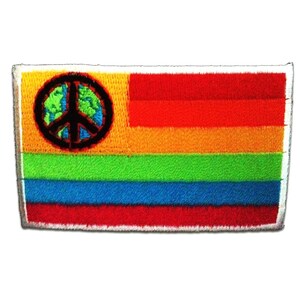 Puede incluir: Parche bordado con un diseño de bandera arcoíris que incorpora un símbolo de la paz y un globo terráqueo. El parche rectangular tiene un borde blanco. Los colores son rojo, naranja, amarillo, verde, azul y un símbolo de la paz negro.
