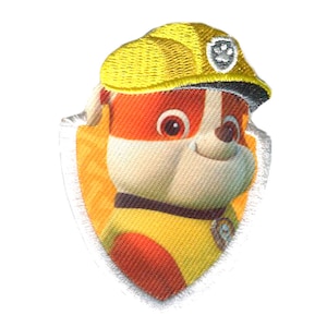 Op de afbeelding: Een geborduurde patch met een cartoonhond die een gele bouwhelm draagt. De hond heeft een wit gezicht en bruine ogen. De patch heeft een witte rand en een poot afdruklogo.