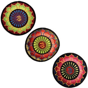 Peut inclure: Trois patchs brodés avec un motif de mandala représentant le symbole Om au centre. Les patchs sont dans différentes combinaisons de couleurs : rouge, jaune et vert ; rouge, orange et vert ; et rose, bleu et vert.