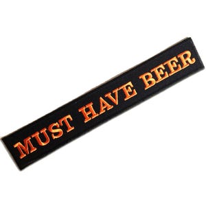 Peut inclure: Un écusson rectangulaire noir avec le texte brodé "MUST HAVE BEER" en orange. Le patch est de conception simple, probablement pour être appliqué sur des vêtements ou des accessoires.
