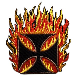 Op de afbeelding: Geborduurde patch met een zwart kruisontwerp met vier gebogen segmenten, omringd door vlammen in rood, oranje en geel. De patch heeft een getextureerd uiterlijk, wat suggereert dat hij van stof is gemaakt.