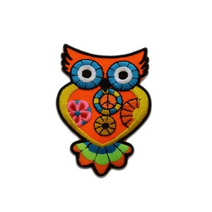 May include: Embroidered owl patch in vibrant colors. The owl features a heart-shaped body with a peace sign, flower, and gear designs. The owl's eyes are blue and white, and the patch has a black border.